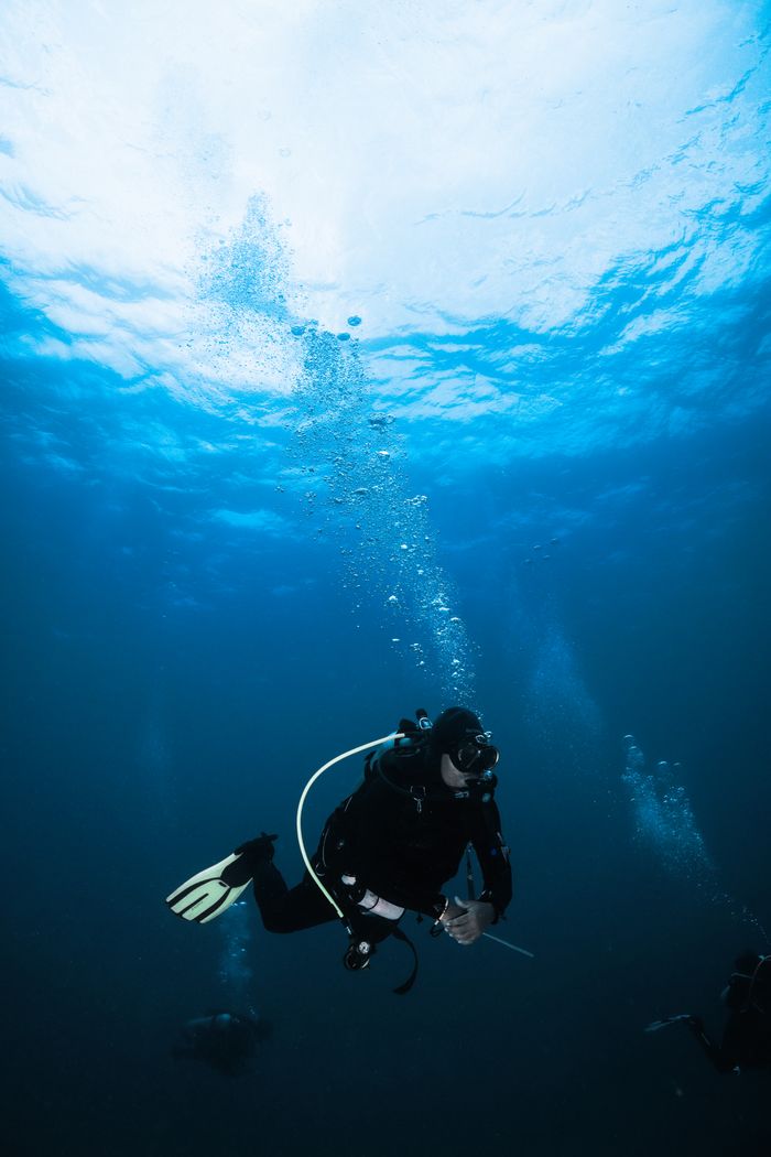 A scuba diver exploring the deep blue waters in Bali, Indonesia. Underwater adventure at its best.